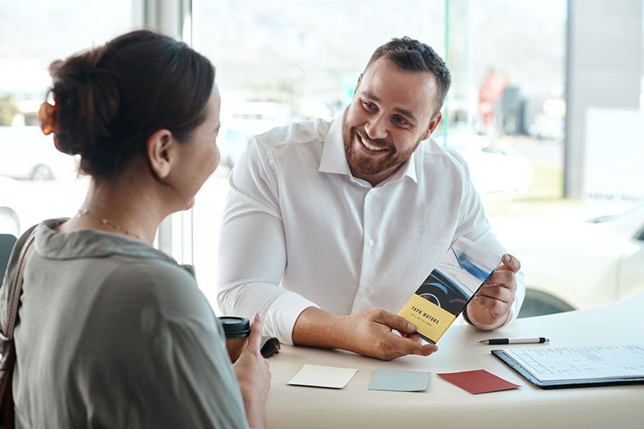 RV dealership representative assisting a customer with RV buying options in a friendly setting.